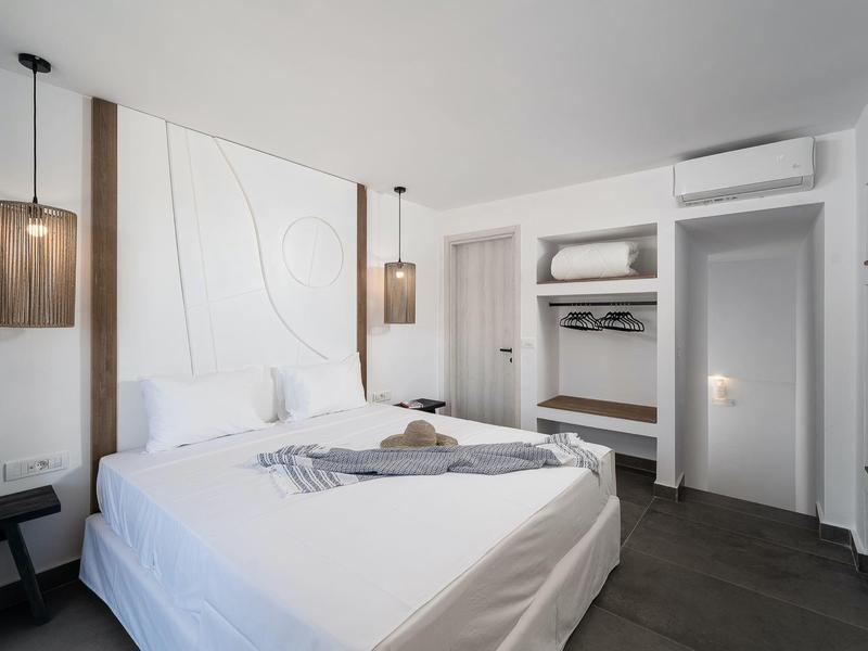 Minimalistische hotelkamer met tweepersoonsbed, modern design en open kledingkast.