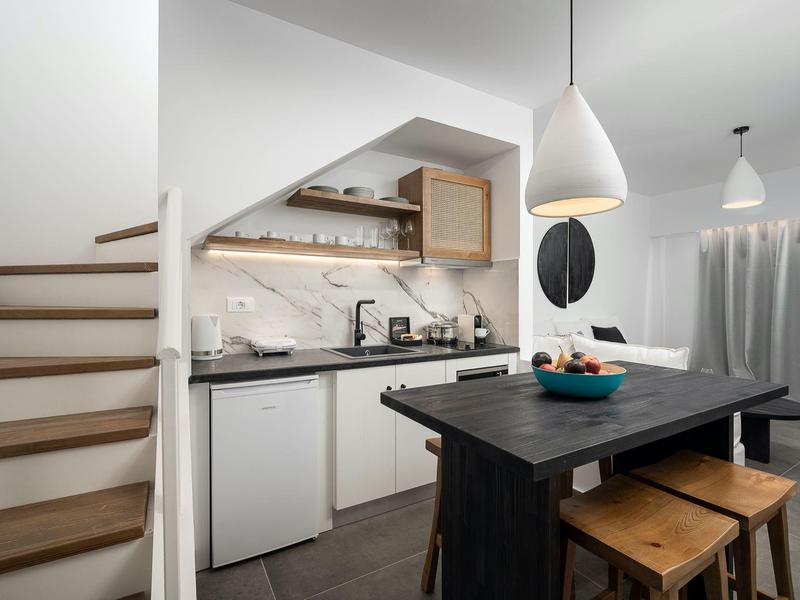 Moderne kleine keuken met houten aanrecht, krukken en trap in lichte ruimte