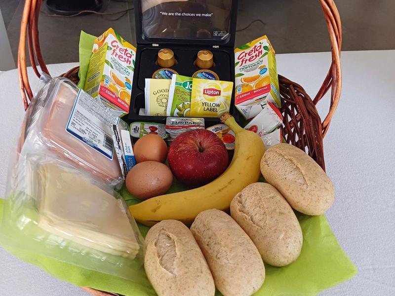 Een mand met ontbijtproducten zoals brood, bananen, eieren en jam.