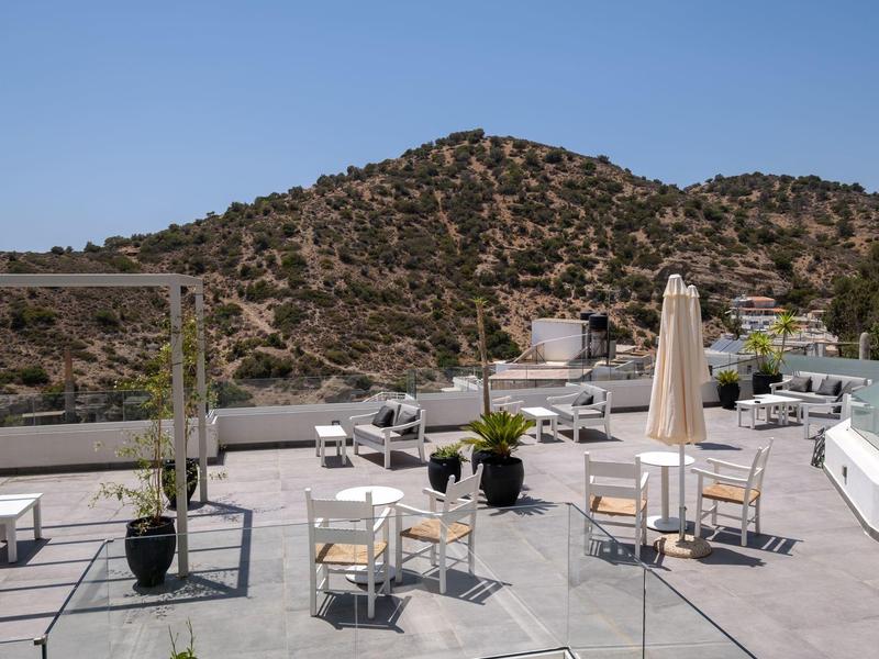 Groot dakterras met tafels, stoelen en bergen op de achtergrond onder een heldere lucht.