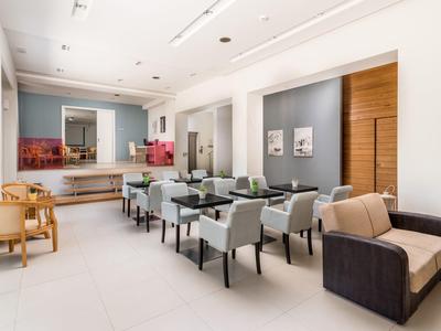 Moderner Aufenthaltsraum mit Stühlen, Tischen, Sofa und heller, offener Raumgestaltung.