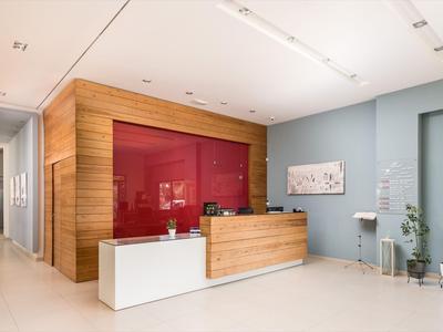 Moderne Hotellobby mit Holzrezeption, rotem Akzentwand und minimalistischer Einrichtung.