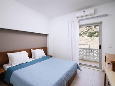 Modernes Hotelzimmer mit Doppelbett, Klimaanlage und Balkon mit Blick auf felsige Landschaft.