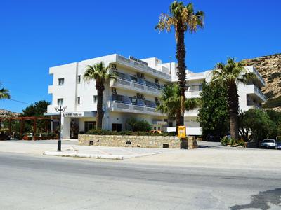 Modernes weißes Hotel mit Balkonen und Palmen unter klarem blauem Himmel.