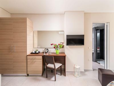 Moderner Hotelzimmerbereich mit Holzschränken, Schreibtisch, Sessel und Fernseher.