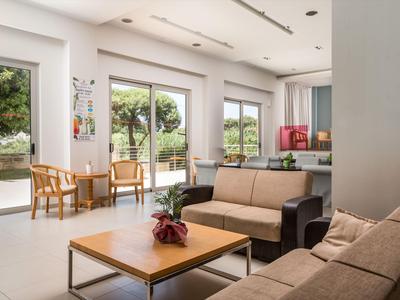 Heller Hotel-Loungebereich mit Sofas, Holzstühlen und großen Fenstern mit Blick nach draußen.