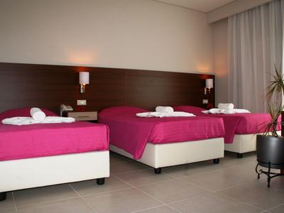 Drei Einzelbetten mit pinken Decken in einem hellen, modernen Hotelzimmer.