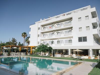 Modernes Hotel mit Pool und mehreren Balkonen unter klarem Himmel.