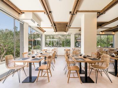 Helles Restaurant mit viel Tageslicht, modernen Holztischen und Stühlen mit Blick auf Garten.