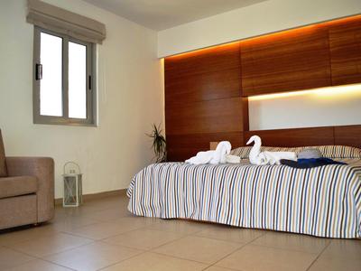 Schlafzimmer mit Doppelbett, gestreifter Bettdecke, zwei Handtuchs-Schwanen und braunen Holzwänden.