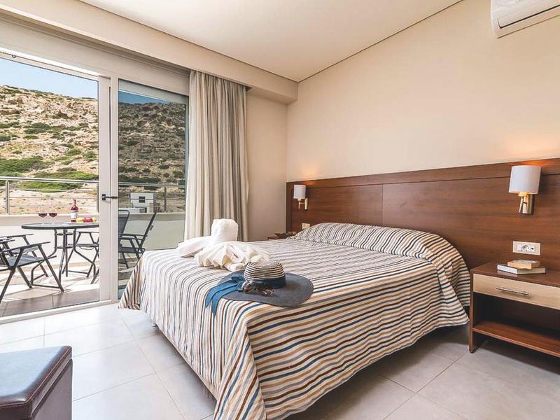 Hell eingerichtetes Schlafzimmer mit Doppelbett, Nachtisch, Balkon und Bergblick.