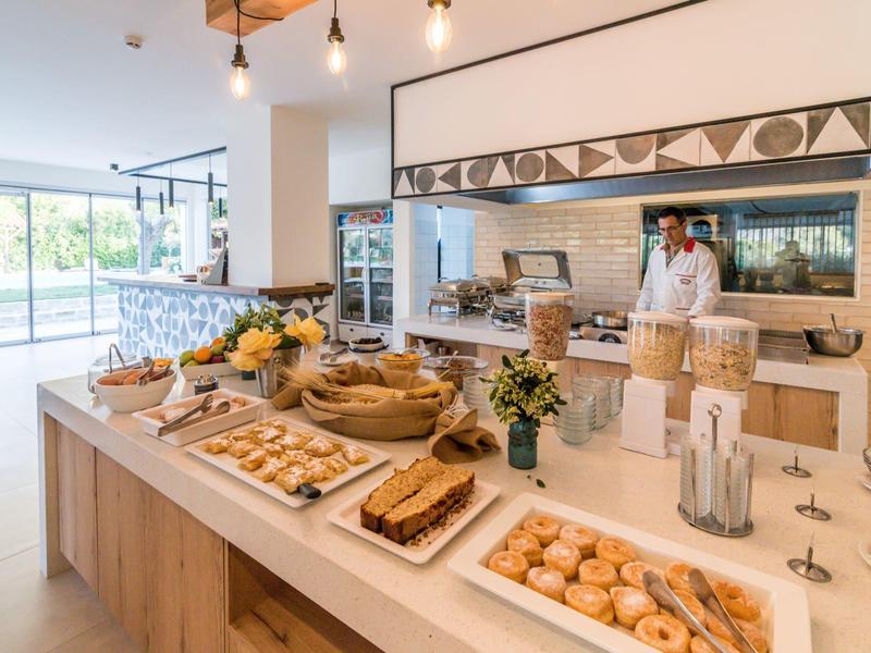 Buffet mit Gebäck, Brot, Müslispendern und Blumen in hellem, modernem Essbereich.