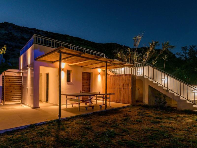 Modernes Haus bei Nacht mit Beleuchtung, Terrasse, Holzverkleidung und Treppe im Außenbereich.