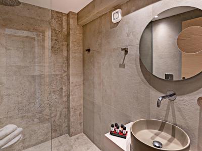 Baño moderno con espejo redondo, lavabo y toallas en tonos neutros.