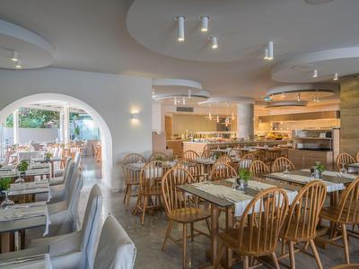 Jasna restauracja z drewnianymi stołami, krzesłami i kominkiem w tle.