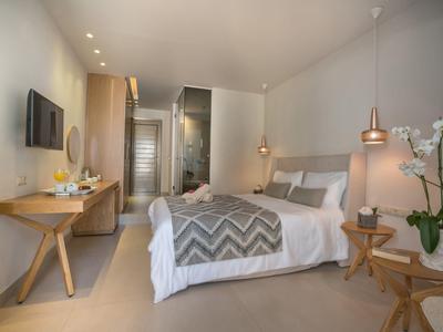 Habitación de hotel moderna con cama doble, muebles de madera e iluminación tenue en tonos neutros.