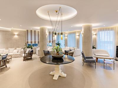 Jasny salon hotelowy z okrągłym stołem, nowoczesnymi krzesłami i dużymi oknami.