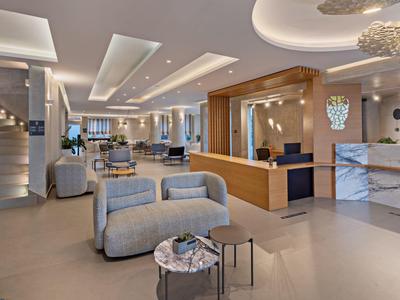 Modern eingerichtete Lobby mit Sesseln, Sitzbereichen, heller Beleuchtung und Marmortresen.