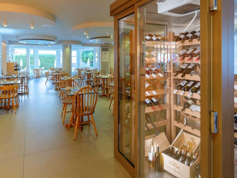 Restaurante bien iluminado con mesas de madera y armario de vinos en un hotel.