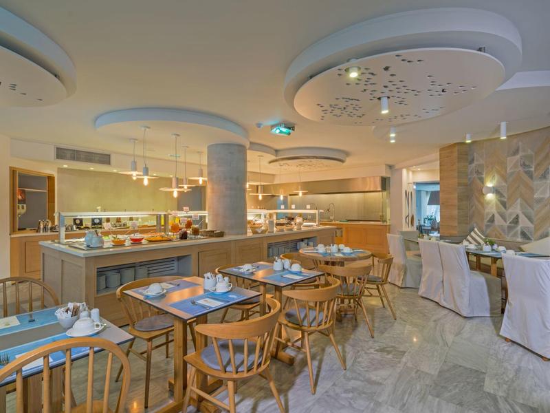 Sala de desayuno moderna con muebles de madera y mesas puestas en ambiente luminoso.