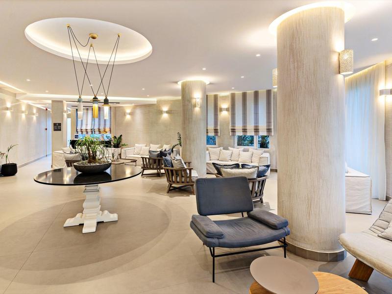 Área luminosa del vestíbulo del hotel con muebles modernos, columnas y mesa decorativa central.