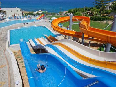 Wasserpark mit mehreren Wasserrutschen und Becken an einem sonnigen Tag am Meer.