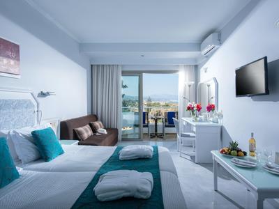 Jasny pokój hotelowy z dwoma łóżkami, widokiem na morze i balkonem.