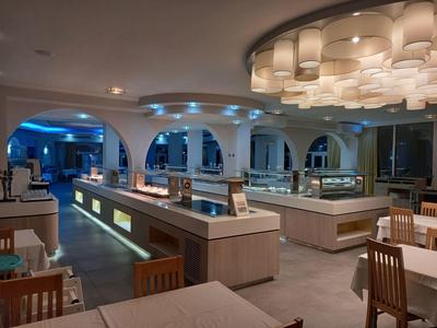 Nowoczesna sala restauracyjna w hotelu z stylowym oświetleniem, drewnianymi krzesłami i czystymi ladami.