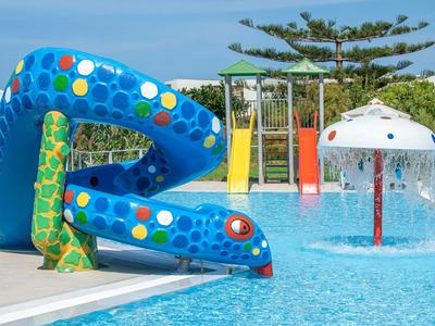 Kolorowa zjeżdżalnia dla dzieci i zabawy wodne na zewnątrz w hotelowym basenie.