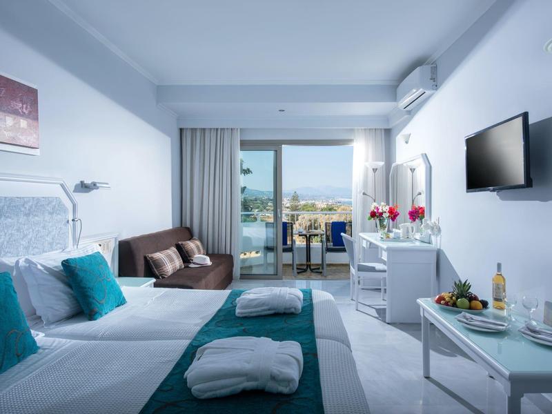 Jasny pokój hotelowy z dwoma łóżkami, widokiem na morze i balkonem.