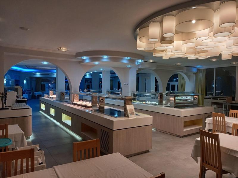 Nowoczesna sala restauracyjna w hotelu z stylowym oświetleniem, drewnianymi krzesłami i czystymi ladami.