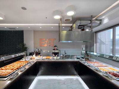 Bufet z różnymi potrawami w nowoczesnej, dobrze oświetlonej restauracji z dużymi oknami.