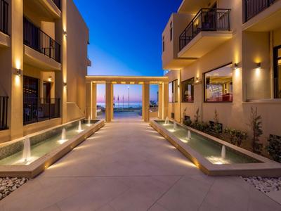 Oświetlony korytarz hotelowy z wodnymi elementami o zmierzchu, w tle widok na morze.