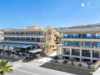 Nowoczesny hotel z żółtą elewacją, wieloma piętrami i tarasem na zewnątrz pod niebieskim niebem.