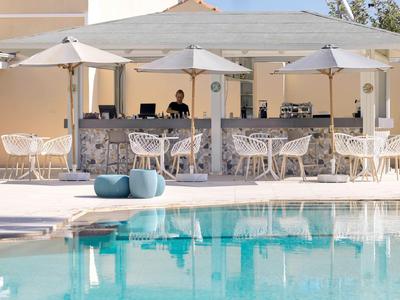 Nowoczesny basen na świeżym powietrzu z barem, parasolami i białymi krzesłami.