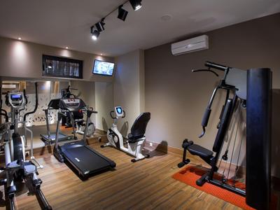 Nowoczesna siłownia z różnymi urządzeniami do ćwiczeń i drewnianą podłogą.