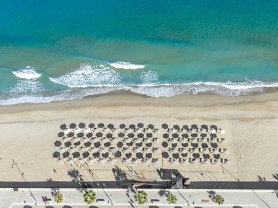 Widok z lotu ptaka na plażę z rzędami parasoli i turkusowym morzem.