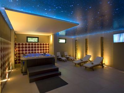 Nowoczesna strefa spa z podgrzewanym basenem, leżakami i nastrojowym oświetleniem pod gwieździstym sufitem.