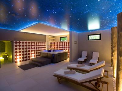 Nowoczesne spa z jacuzzi, leżakami i gwiaździstym oświetleniem sufitowym.
