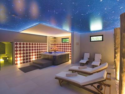Moderner Wellnessbereich mit Whirlpool, Liegestühlen und beleuchtetem Sternenhimmel.