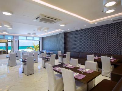 Modernes, helles Restaurant mit weißen Stühlen und dunklen Holztischen in einem Hotel.