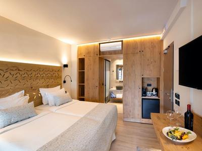 Modernes Hotelzimmer mit großem Doppelbett, Holzvertäfelung und integriertem Kleiderschrank mit Spiegel.