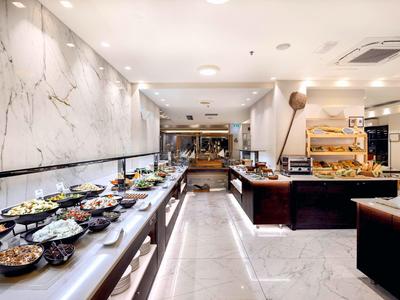 Bufet z różnorodnymi potrawami w nowoczesnej restauracji z marmurowymi ścianami i jasnym oświetleniem