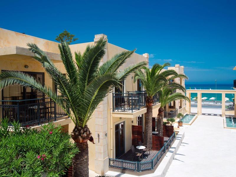 Blick auf ein Hotel mit Palmen und Blick aufs Meer bei blauem Himmel.