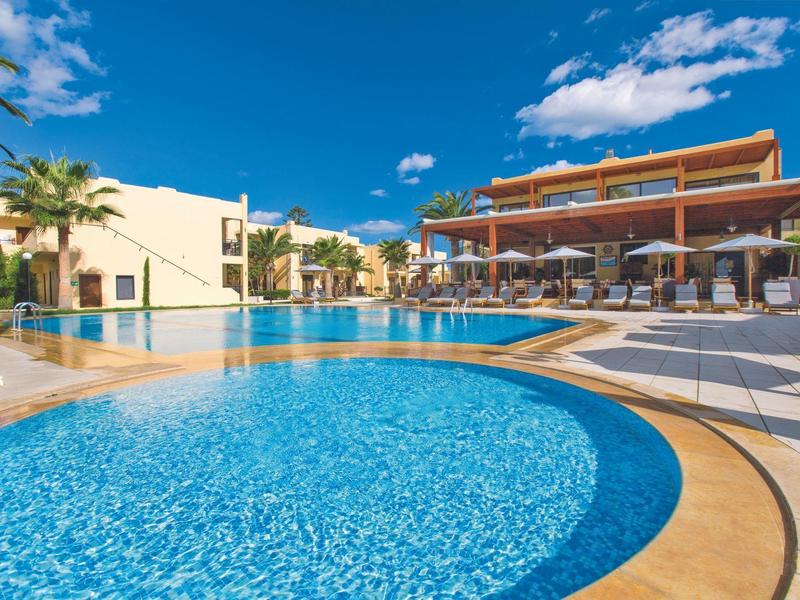 Moderner Hotelpool mit Sonnenschirmen und Liegestühlen unter klarem blauem Himmel.