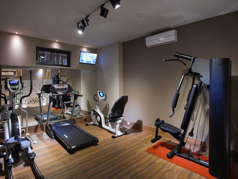 Moderner Fitnessraum mit verschiedenen Trainingsgeräten und Holzboden.