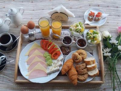 Vassoio per la colazione con affettati, croissant, succhi, uova e fiori sul tavolo.