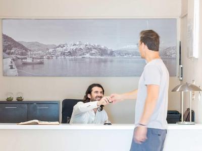 Un receptionist dell'hotel saluta un ospite con una stretta di mano alla reception.