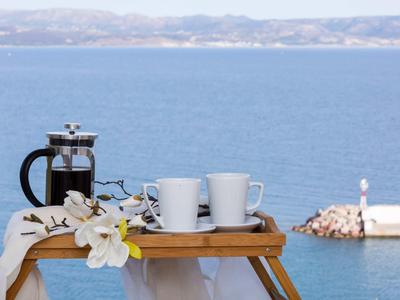 Caffettiera francese, due tazze e fiori su un vassoio con vista mare.