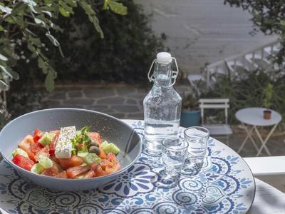 Ciotola con insalata e caraffa d'acqua su tavolo esterno decorato blu e bianco.